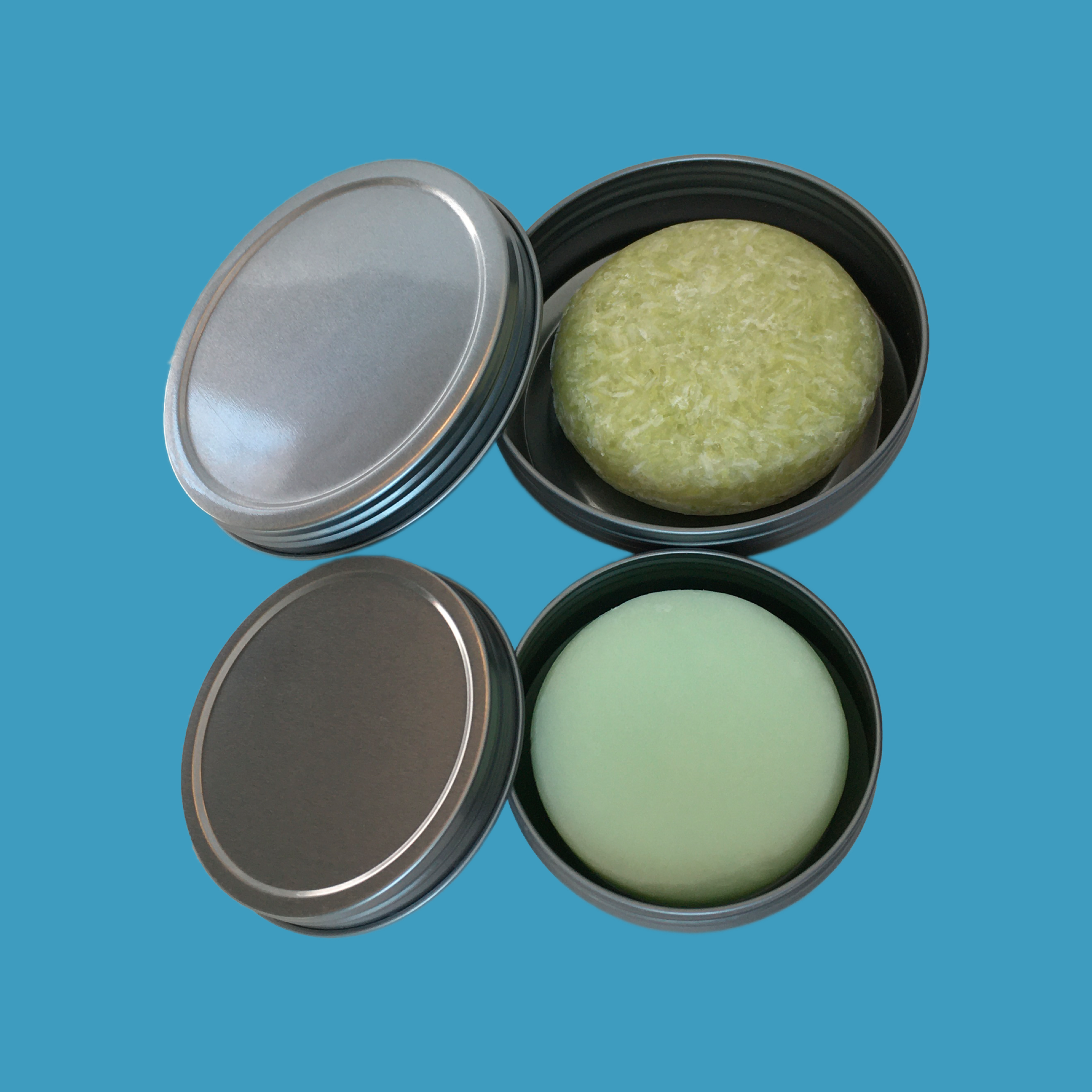 Two tins on blue background with Green Ablutions zero waste sustainable plastic free shampoo and conditioner for travel, camping or home use by the whole family. 